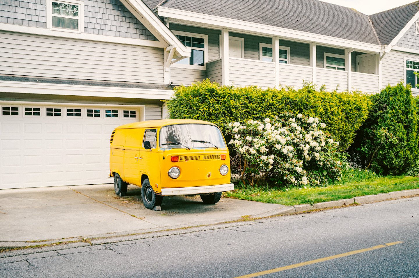 A yellow vintage delivery van parked on a concrete driveway.