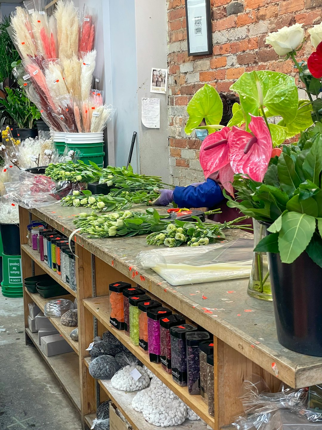 Florist arranging light green flowers on a wooden workbench.
