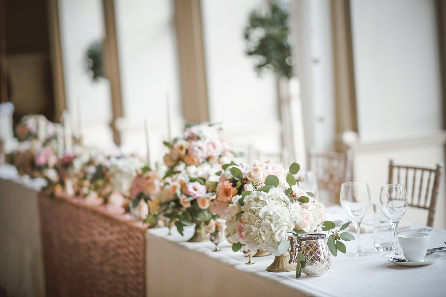 Elegant wedding reception table set with floral centerpieces and candles.