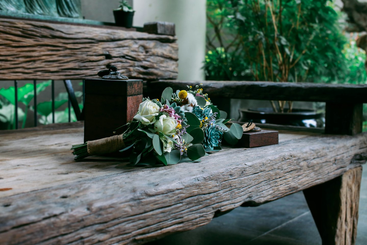 A floral bouquet wrapped in burlap sits on a wooden table.