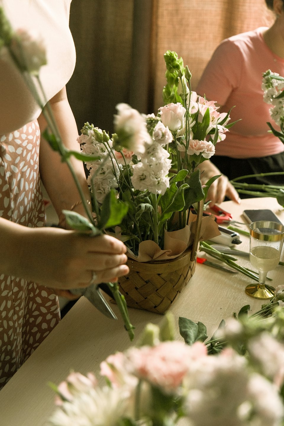 Two people arranging fresh flowers with shears.