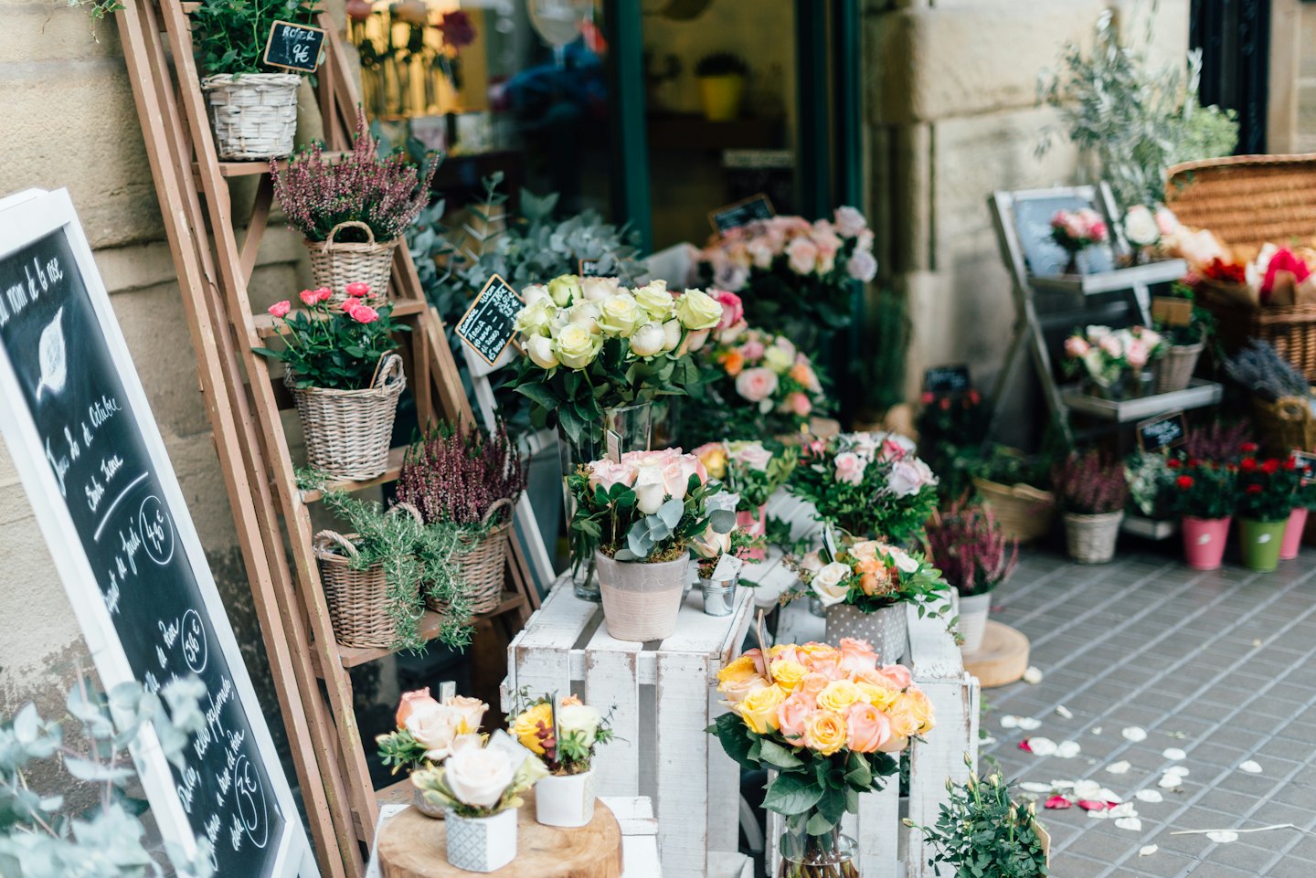 Flower shop display with potted plants and bouquets on crates and ladders.