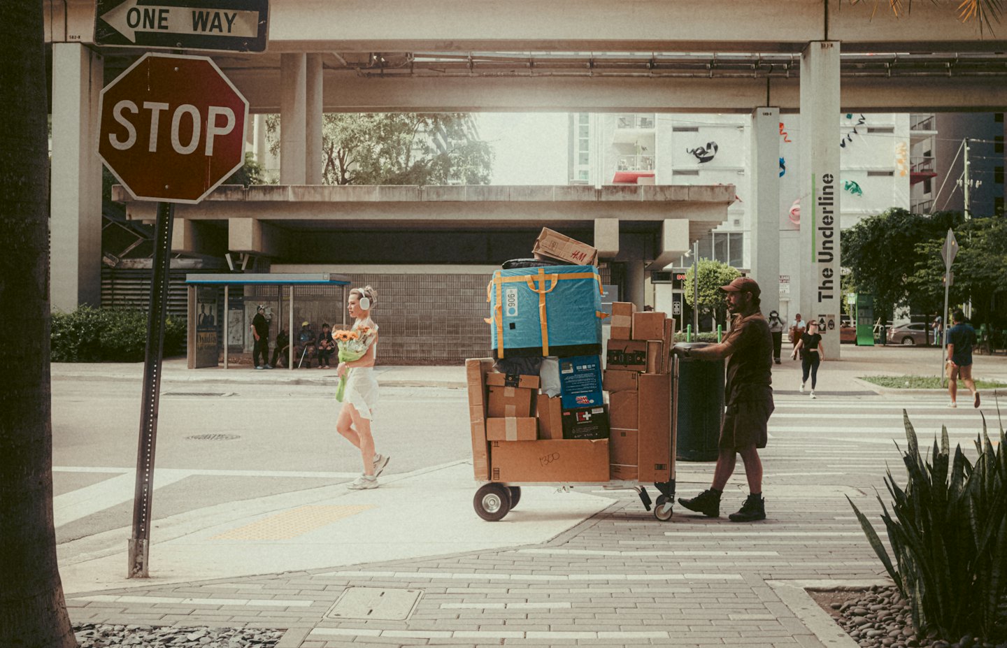 Delivery worker pushes a cart of boxes past a pedestrian.